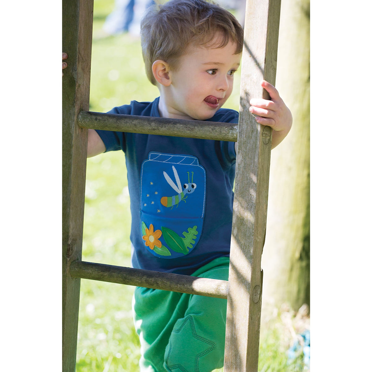 Junge mit dunkelblaues kurzarmshirt mit Leuchtkäfer applikation von der Marke Frugi