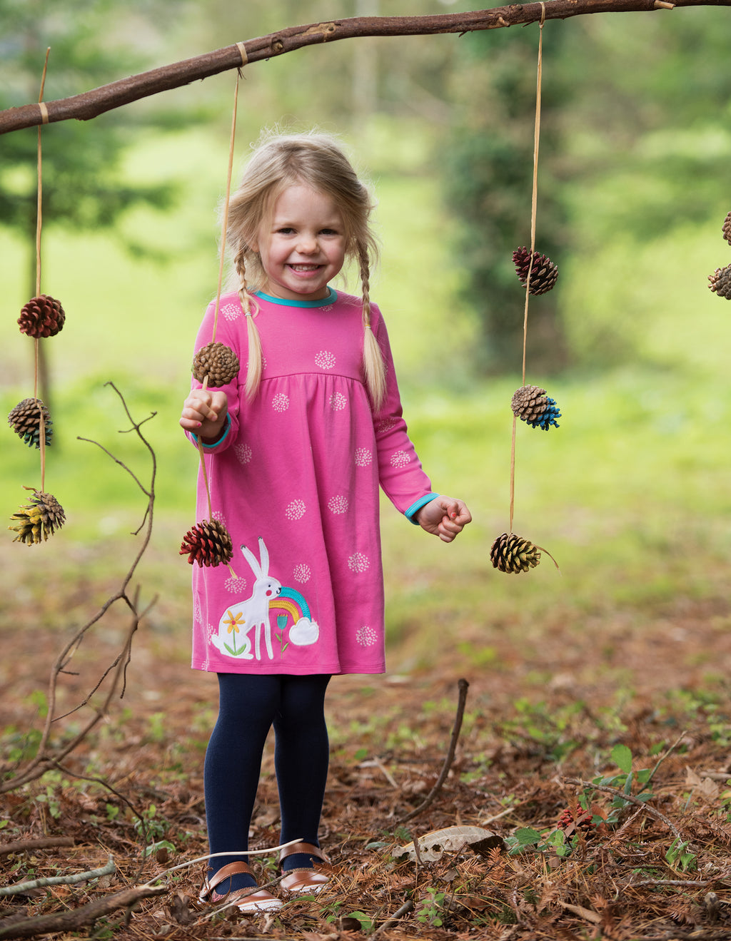 Mädchen mit Kleid Has in Pink von der Marke Frugi